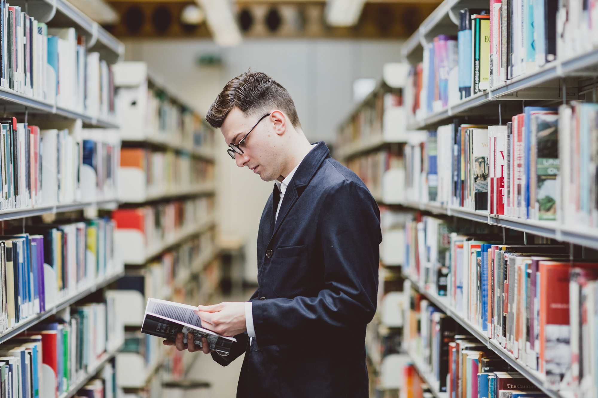 History Lecturer Dr William Tullett in the library reading a book