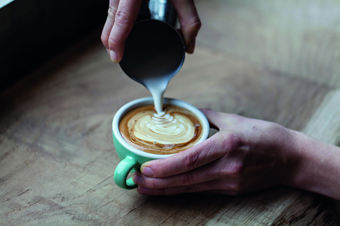 Cream being poured into a cup of coffee