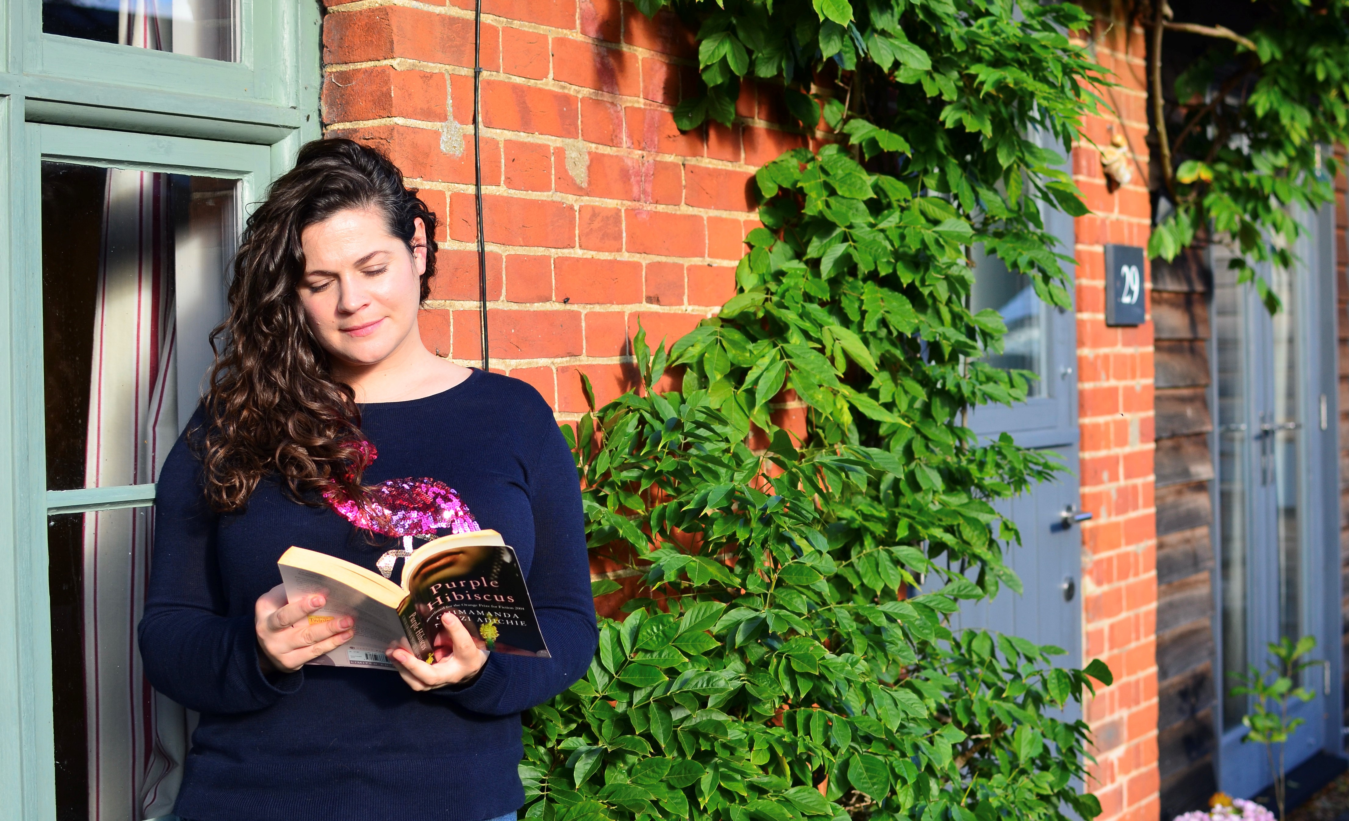 Charlotte Quince reading a book outside her house