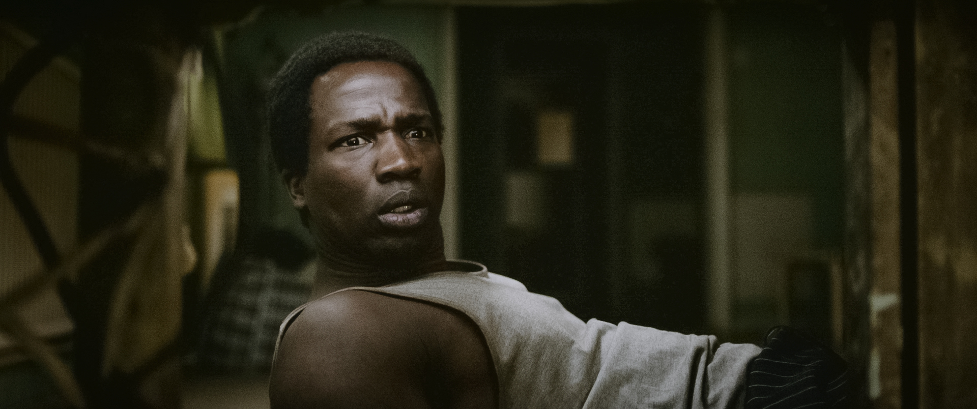 Still from 'His House' showing man lying back looking worried