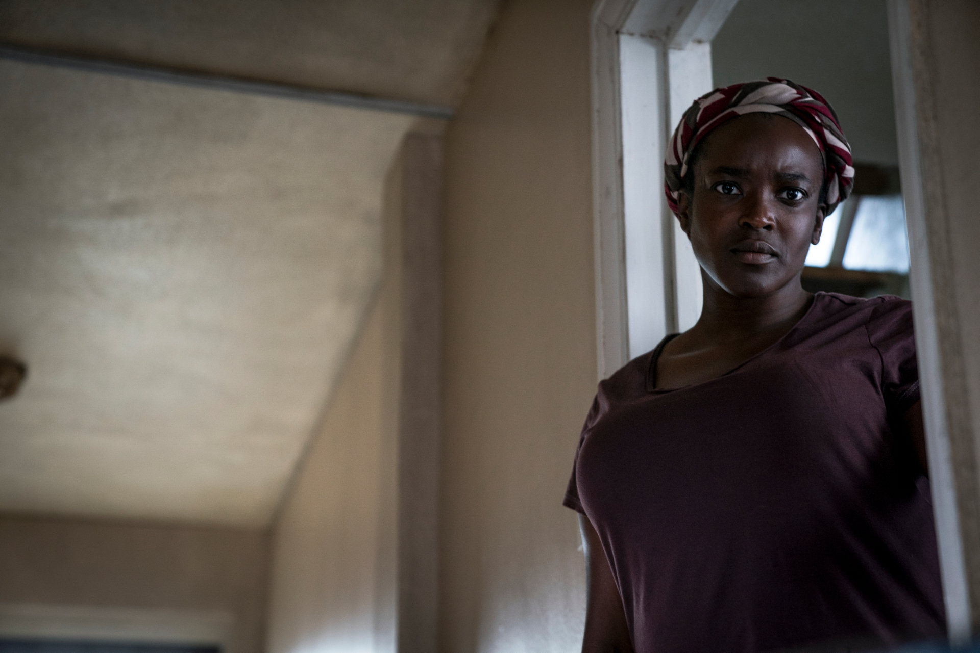 Still from 'His House' showing woman in undecorated room