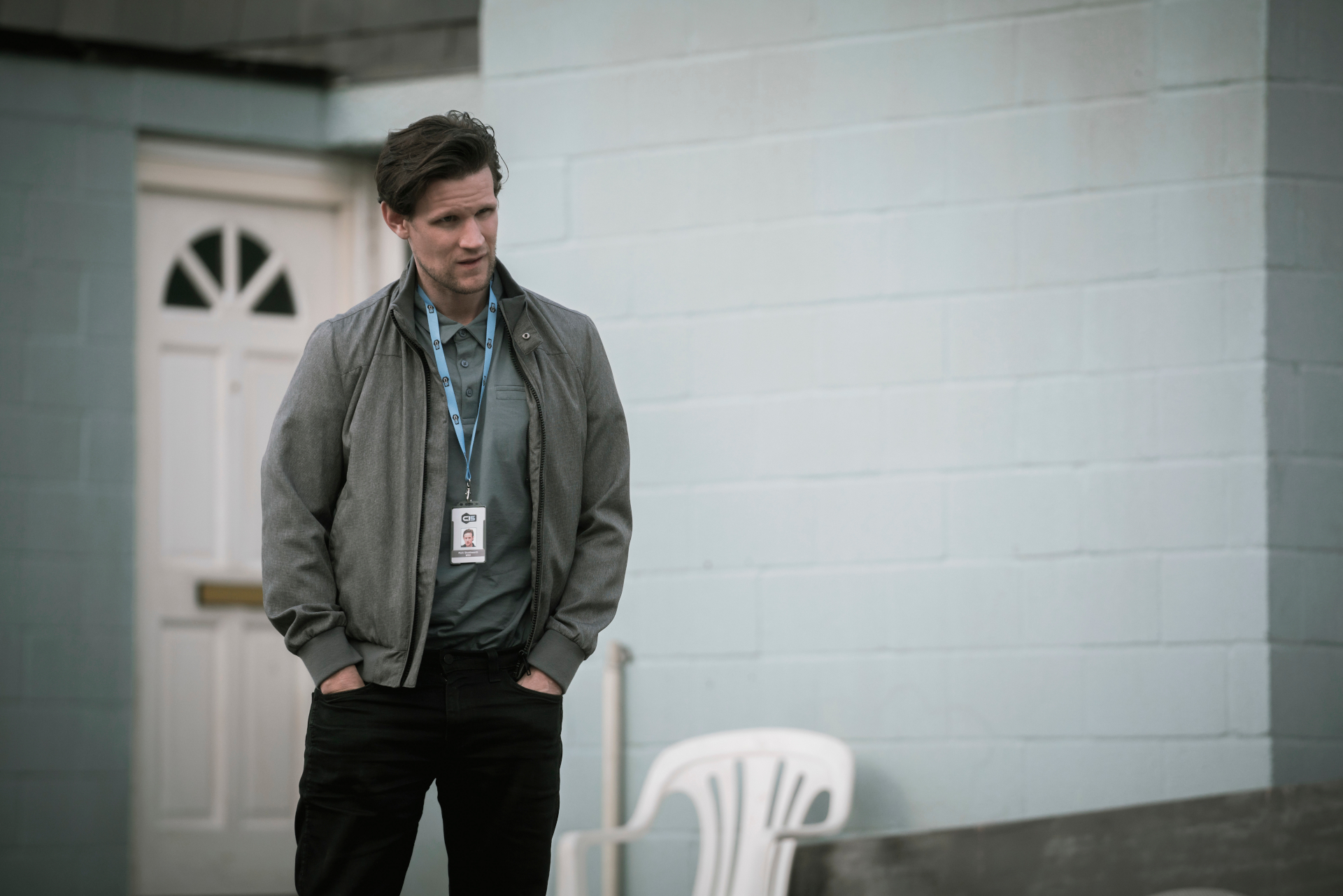 Still from 'His House' showing man outside with hands in pockets